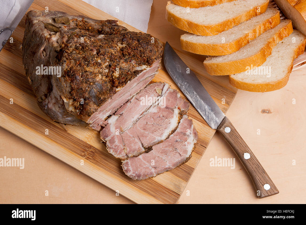 Würzige Fleisch gebacken mit Kräutern und Gewürzen auf Holzbrett. Stil überbackene würzige Landschinken. Ein saftig frisch gebackenes Schweinefleisch auf Holzbrett Stockfoto