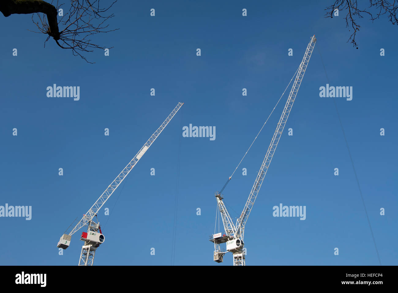 zwei Turmdrehkrane gesehen vor einem blauen Himmel auf einer Baustelle in Kingston nach Themse, Surrey, england Stockfoto