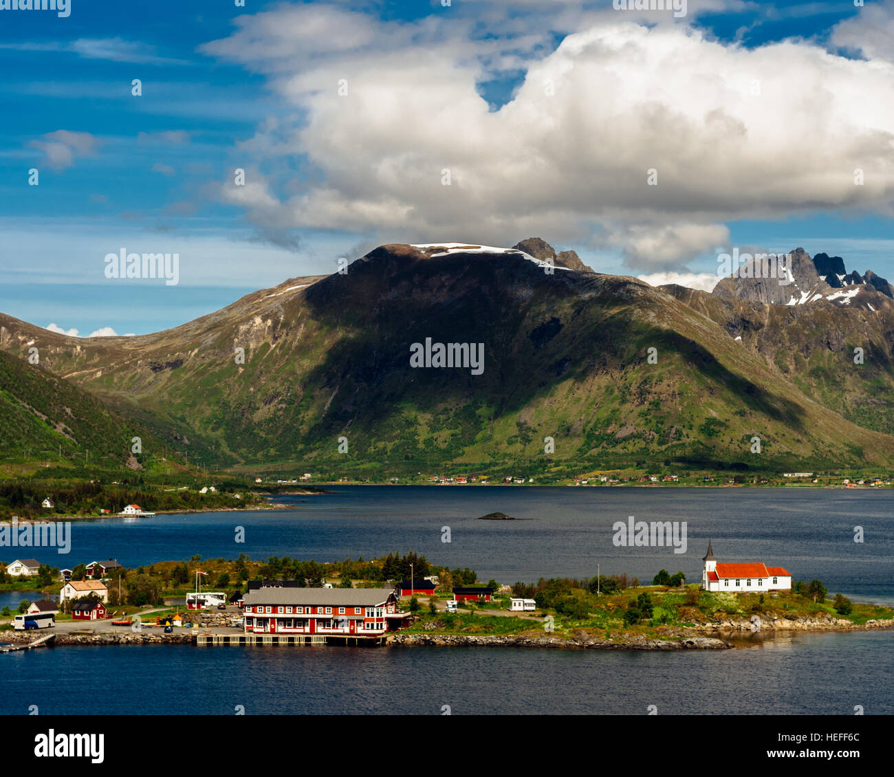 Klassische norwegische skandinavische Sommerlandschaft mit Bergen, Fjord, See und eine Kirche mit einem blauen Himmel, Norwegen, Lofoten-Inseln Stockfoto
