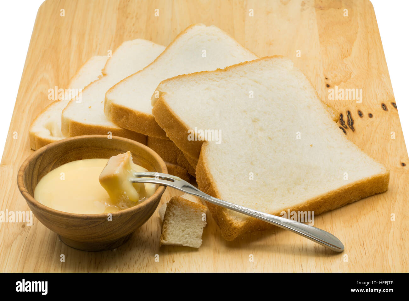 Portion Brot dip in gezuckerte Kondensmilch auf Holzbrett Stockfoto