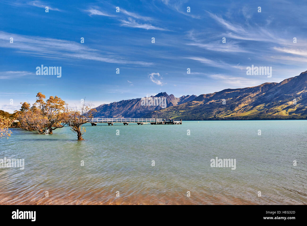 Neuseeland, Südinsel, Glenorchy, Langer Holzsteg Führt in See, Berge Umranden, Klares Wasser, Malerisch, Bäume Ragen aus Wasser Stockfoto