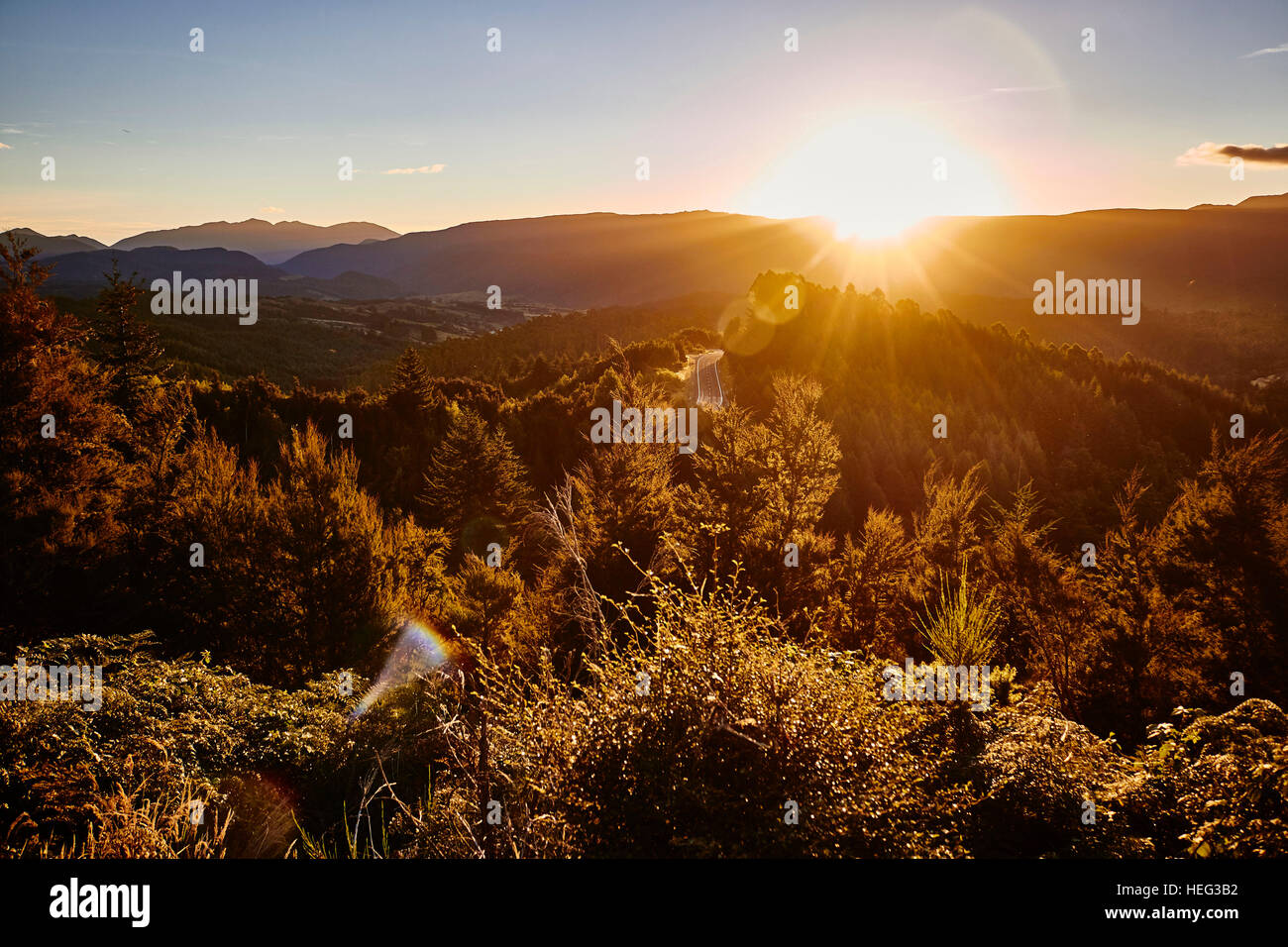 Neuseeland, Südinsel, Anzeigen der Hoffnung Bank, dichten Wald in den Sonnenuntergang, Straße für Berglandschaft, die Sonne verschwindet hinter den Gebirgsketten am Horizont Stockfoto