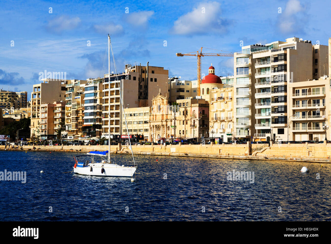 Yacht vor Anker in Sliema Creek, Valletta, mit Hotels und Kirche hinter. Stockfoto