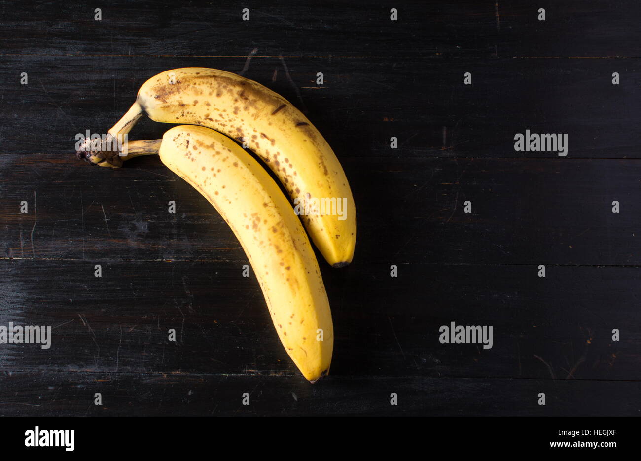 Zwei reife Bananen auf dunklem Holz Stockfoto