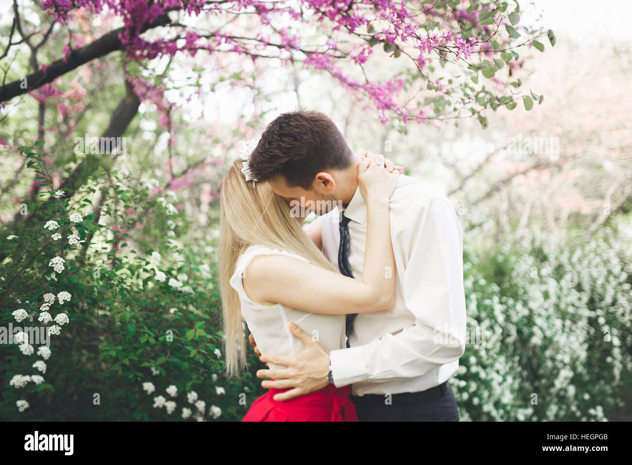 Stilvolle schöne glückliche Hochzeit paar küssen und umarmen im Botanischen Garten Stockfoto