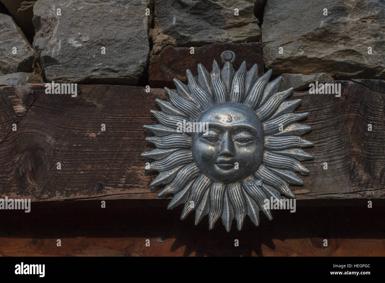 Sonnensymbol hängt an der Wand aus Holz und Stein Stockfoto