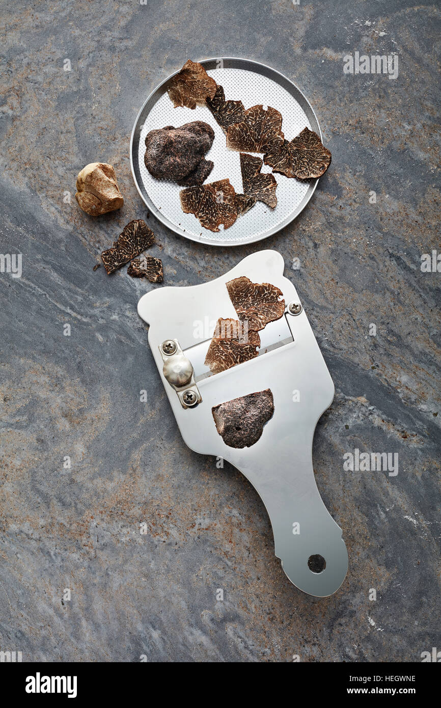 Schwarze Trüffel geschnittene Scheiben Schneidemesser Klinge dünn teure Delikatesse Pilz Chef Zutat Rasieren Schweineruch starker Waffel Luxus Ascomycete Pilz Stockfoto