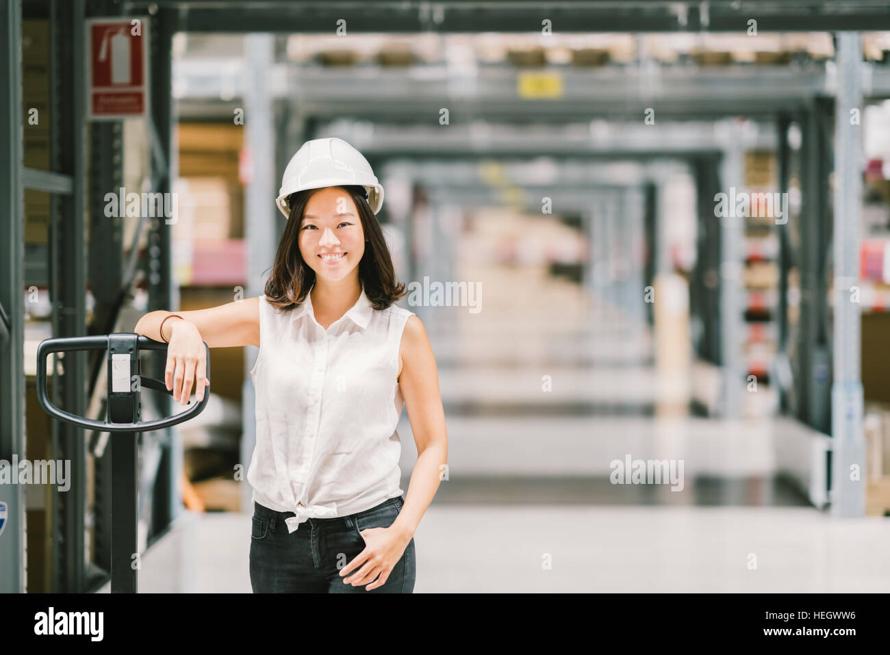 Schöne junge Ingenieur oder Techniker Asiatin lächelnd, Lager oder Fabrik zu verwischen, Hintergrund, Industrie oder Logistik-Konzept mit Textfreiraum Stockfoto