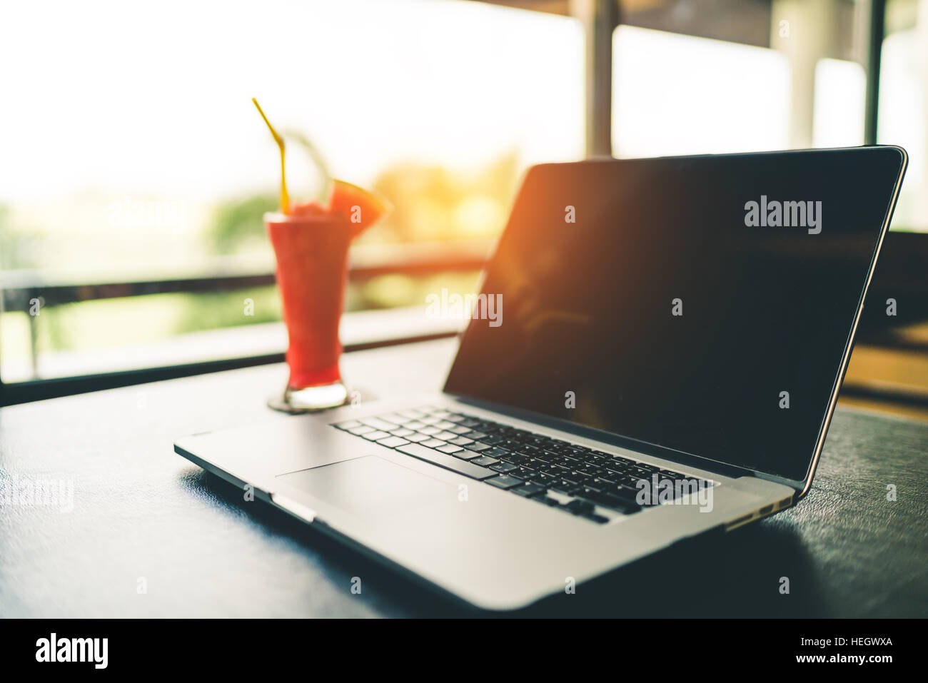 Laptop mit Wassermelonensaft auf Garten Unschärfe Hintergrund, langsam Leben oder freiberuflich oder Business-Travel-Konzept, Vintage-Ton mit warmen Lichteffekt, Tiefe Stockfoto