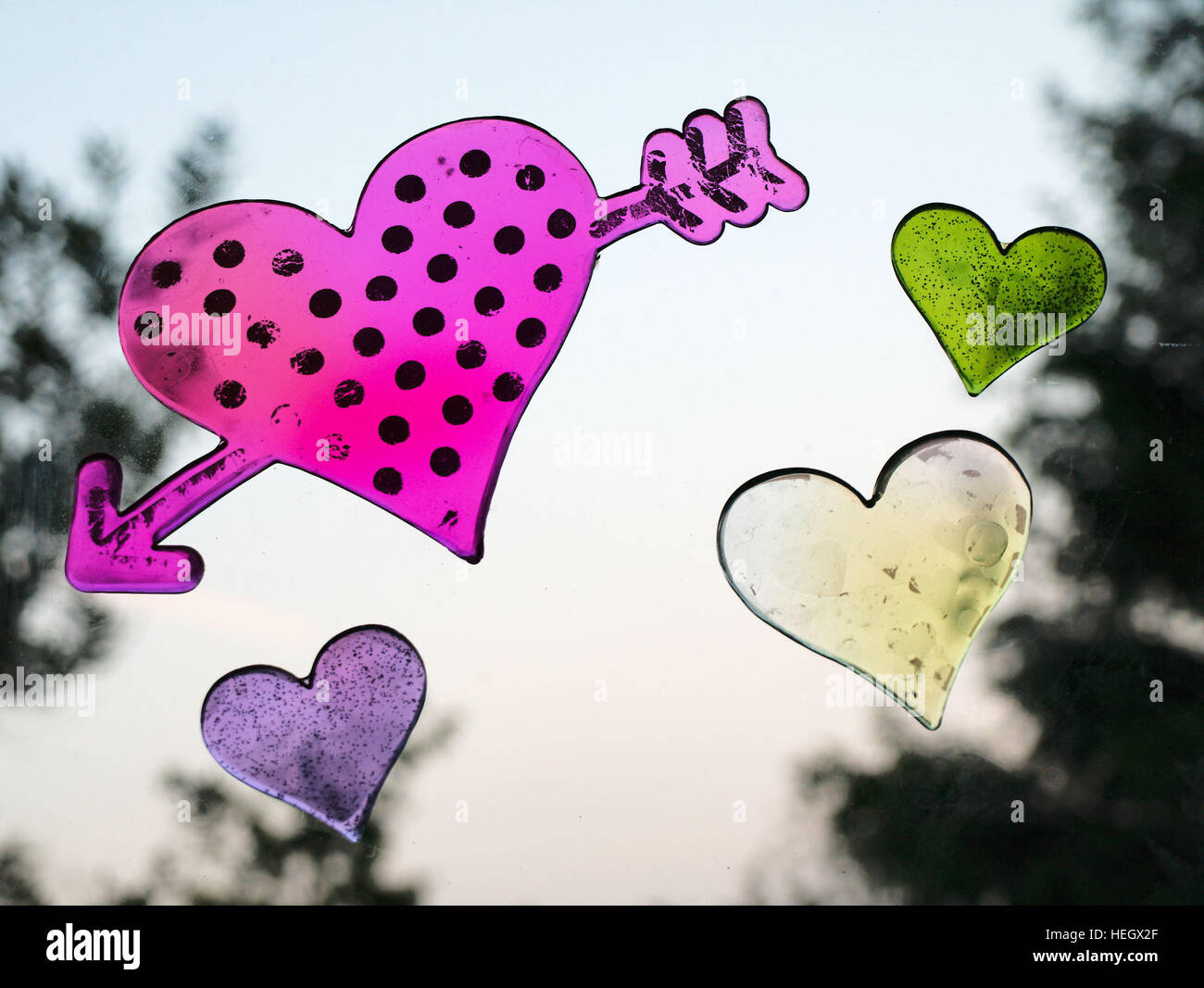 Eine kühne Pfeil durch Herzsymbol umgeben von kleineren farbigen Herzen. Stockfoto