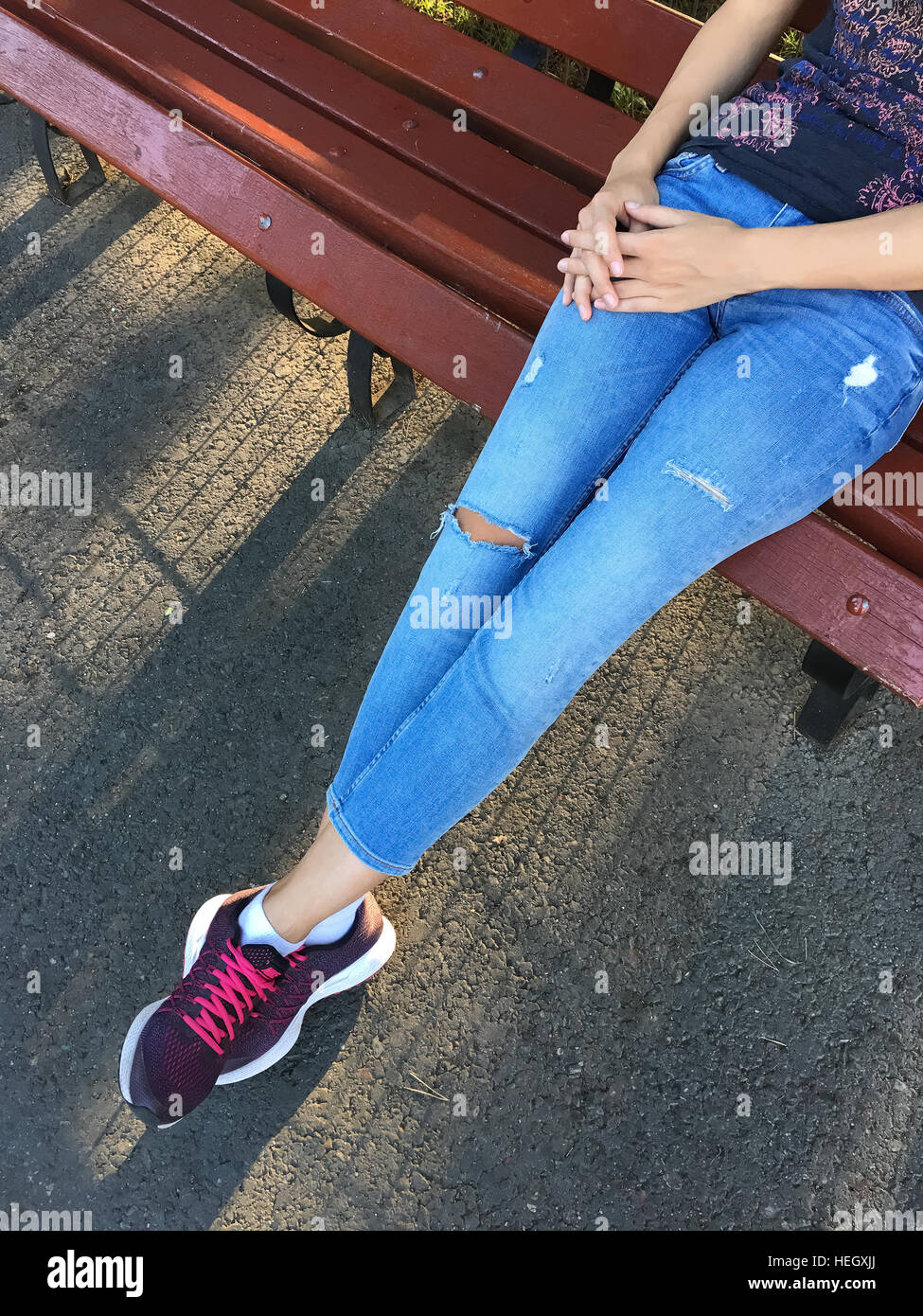 Mädchen In entspannten Casual-Outfit auf Parkbank Stockfoto