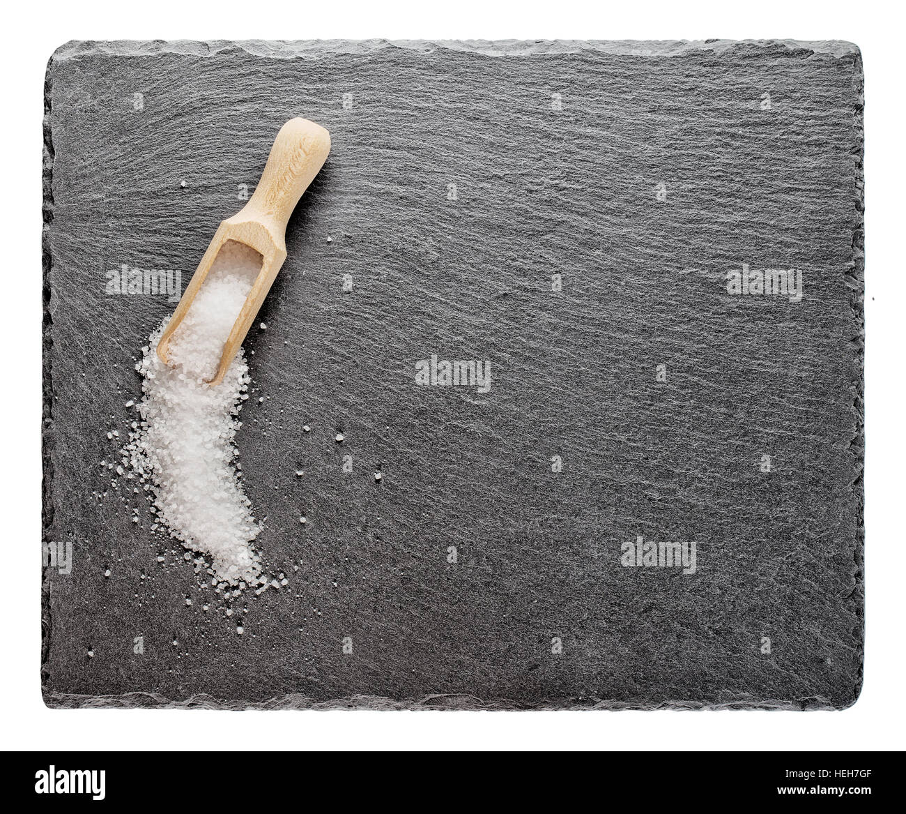 Salz mit einem Holzlöffel auf Schiefer Tafel isoliert auf weißem Hintergrund Stockfoto