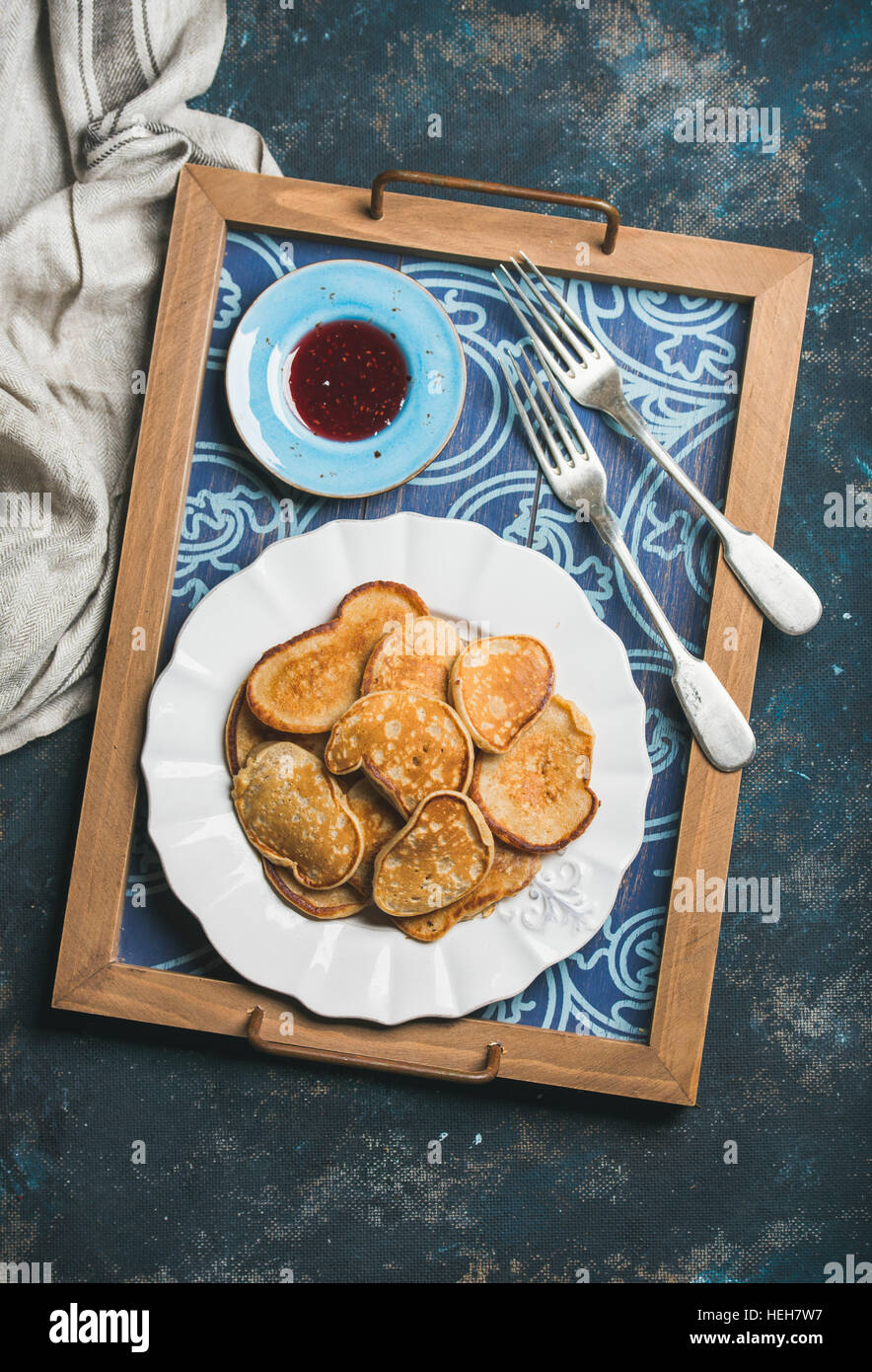 Frühstückstablett mit Vollkorn-Pfannkuchen und Himbeermarmelade. Ansicht von oben, schäbig dunkelblauen Hintergrund Stockfoto