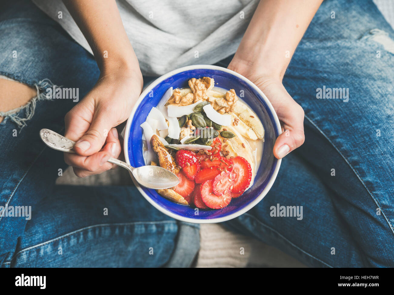 Essen gesundes Frühstück Schale. Joghurt, Müsli, Samen, frische und getrocknete Früchte und Honig in blauen Keramikschale in Frau ' s Hände. Sauber, Essen, Diät, d Stockfoto