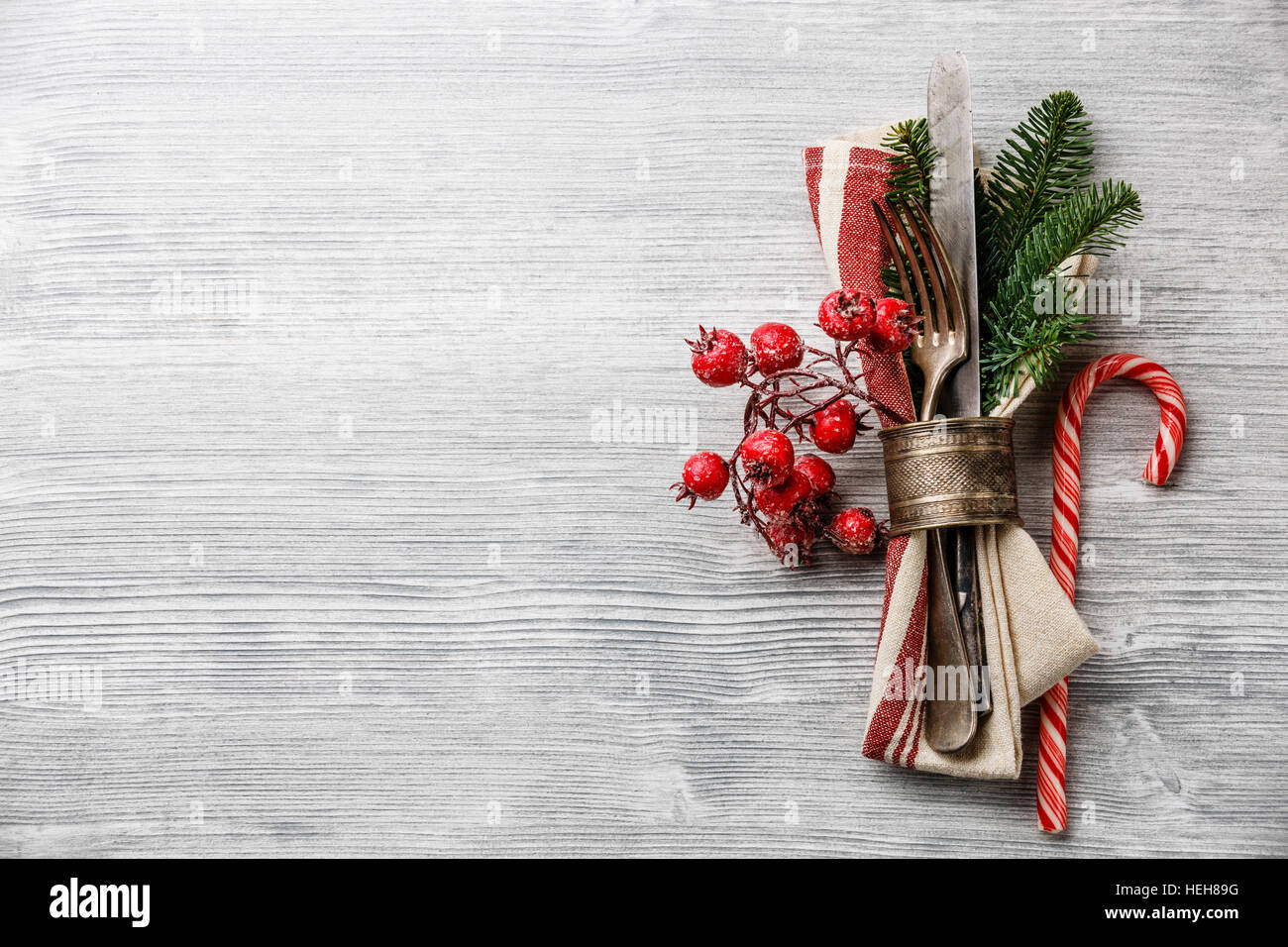 Tabelle-Gabel und Messer set mit Serviette, Weihnachten Tanne Zweig, roten Beeren und Serviettenring auf grauem Holz Hintergrund Textfreiraum Stockfoto