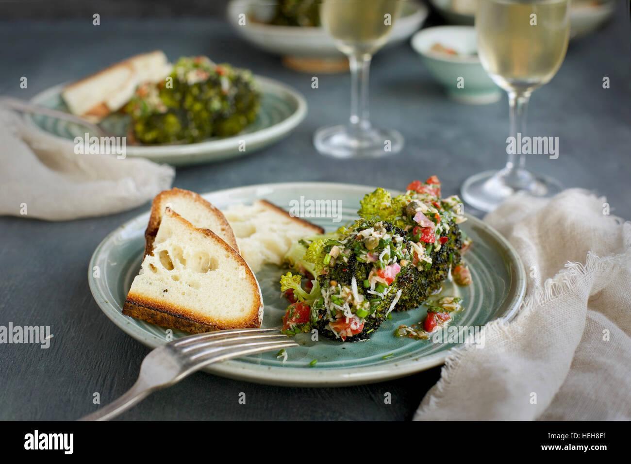 Mangold-Brokkoli mit Tomaten italienische Stil Salsa Verde serviert mit Brot und Weißwein. Davonsausen aus Draufsicht auf eine grün/grauen Hintergrund. Stockfoto