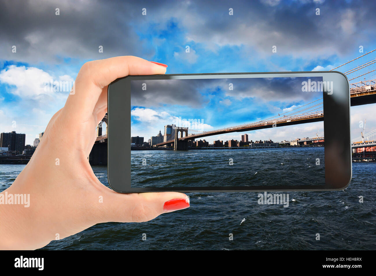 Zeigen Sie über Brooklyn Bridge, New York mit Frau Hand aufnehmen eines Bildes mit Smartphone an Stockfoto