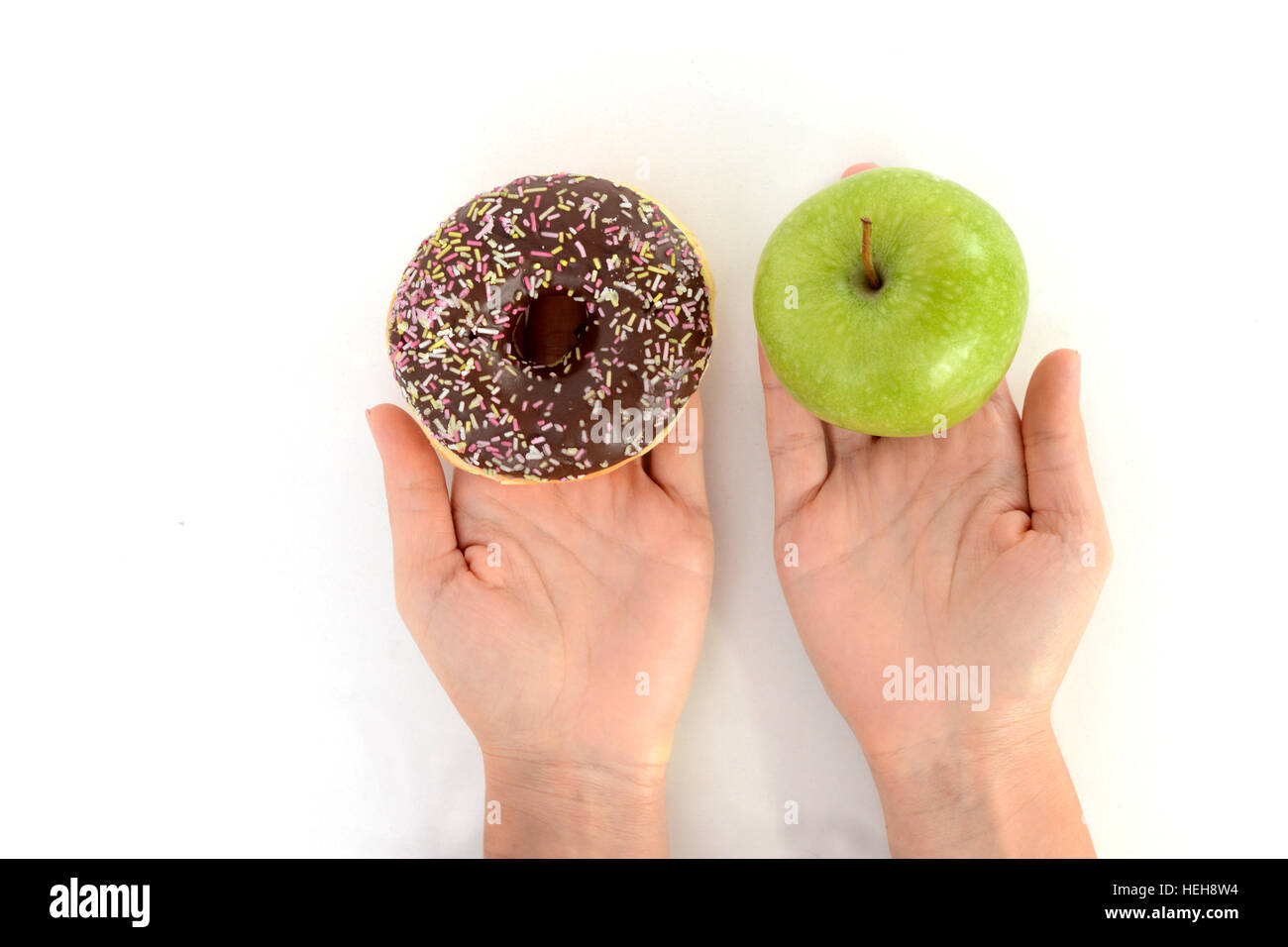 Gesunden Lebensstil oder Ernährung Konzept mit jungen Frau, die in den Händen halten, einen grünen Apfel und einen donut Stockfoto