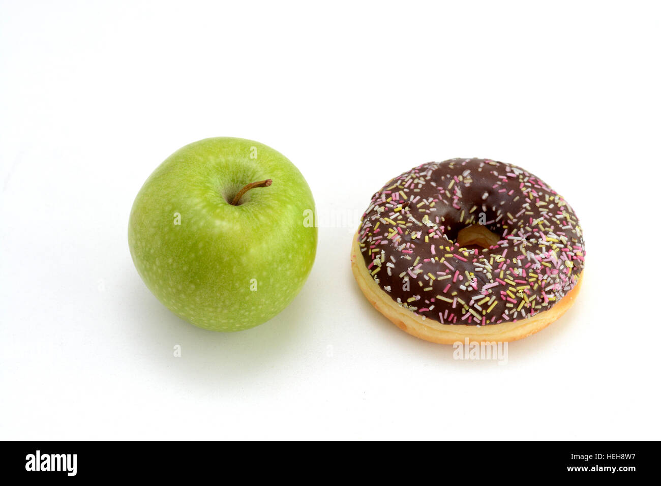 Die Wahl zwischen gesunden Früchten und Süßigkeiten. Grüner Apfel und leckere Schoko donut Stockfoto