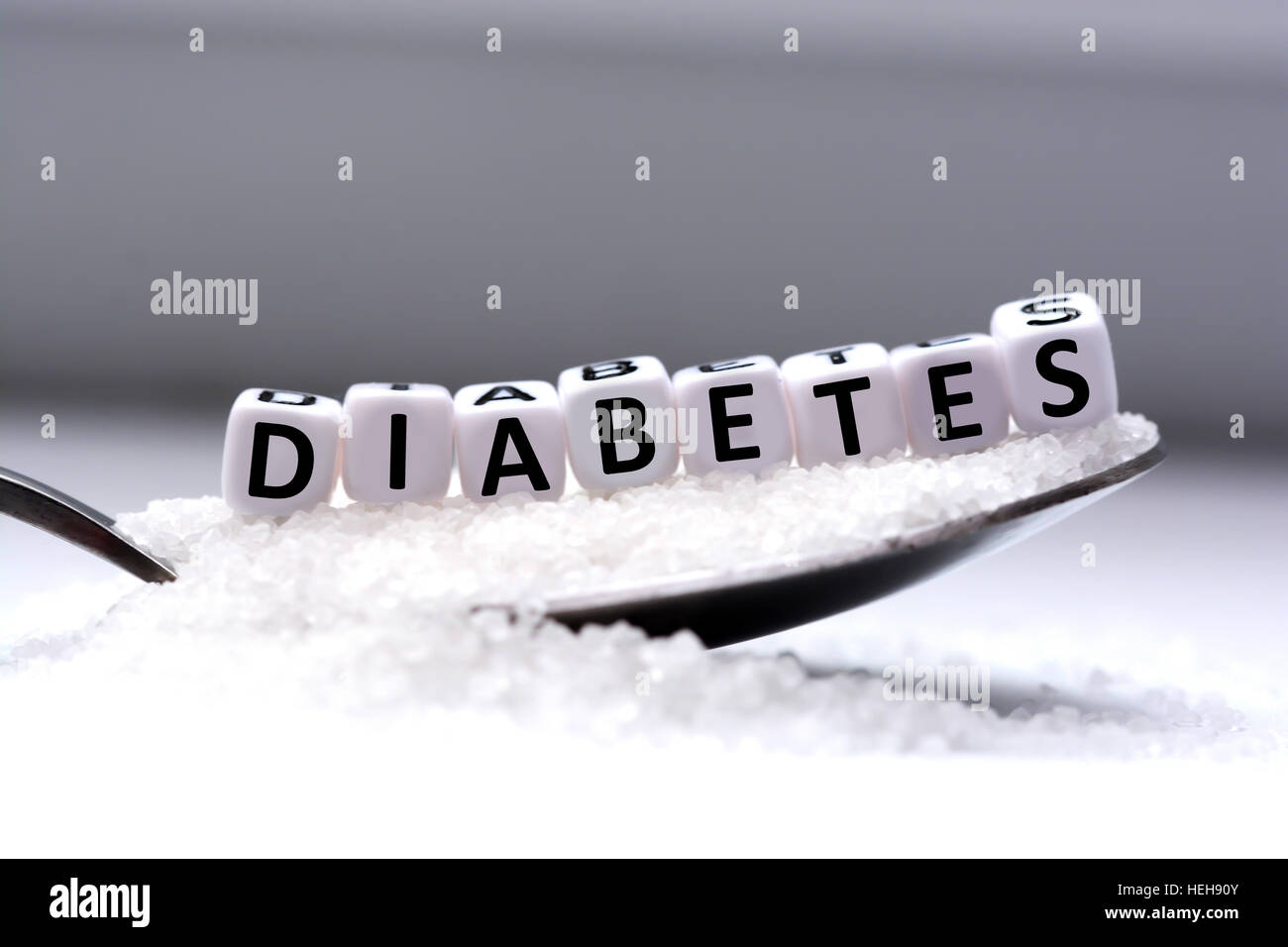 Plastische Buchstaben Perlen Schreibweise "Diabetes" in einen Löffel voll Zucker Stockfoto