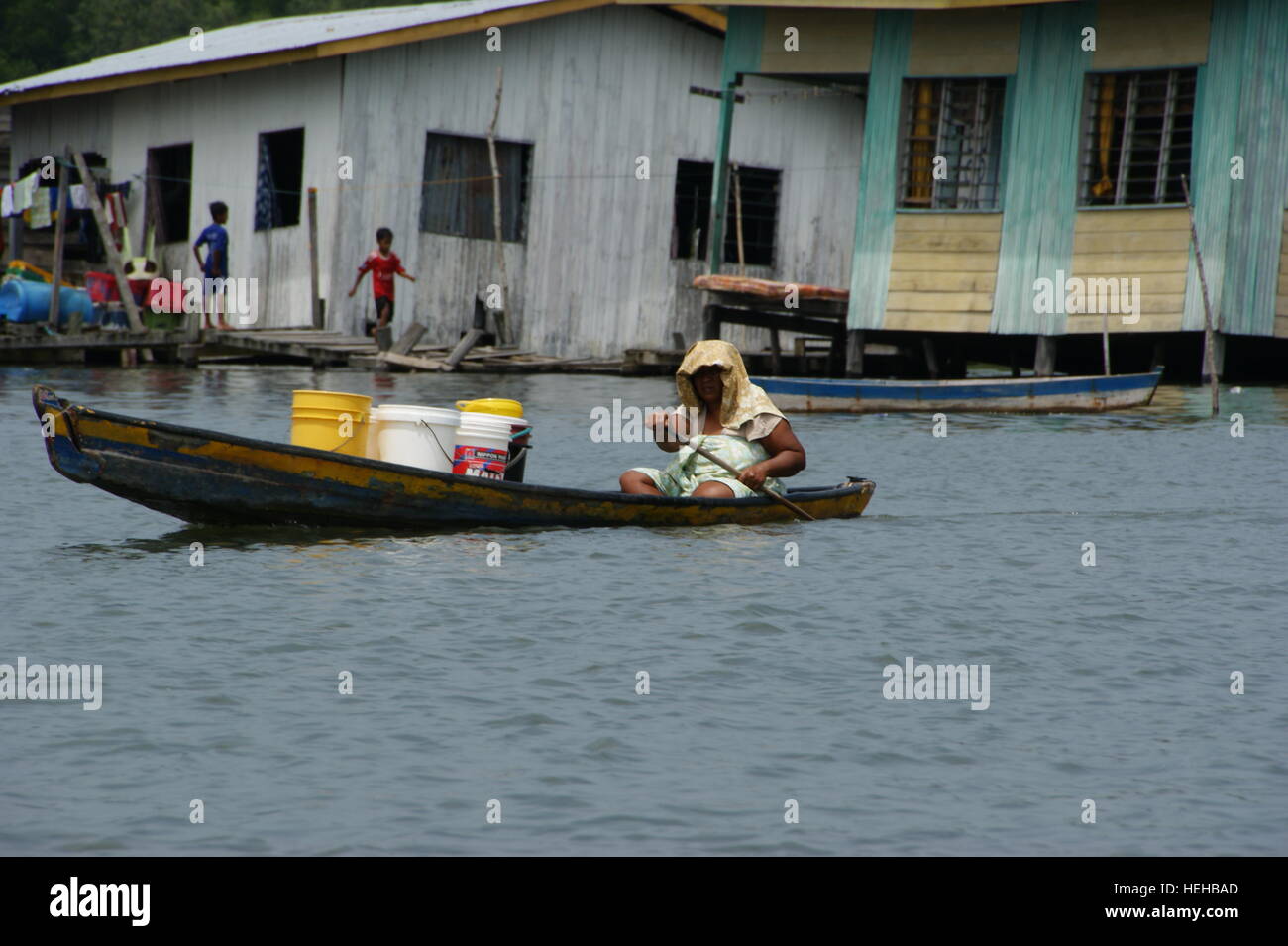 Frau trägt ein frachtboot. Fischerdorf auf dem Wasser. Mengkabong Fluss, Kota Kinabalu, Sabah, Borneo, Malaysia. 22 Jun 2012 Stockfoto