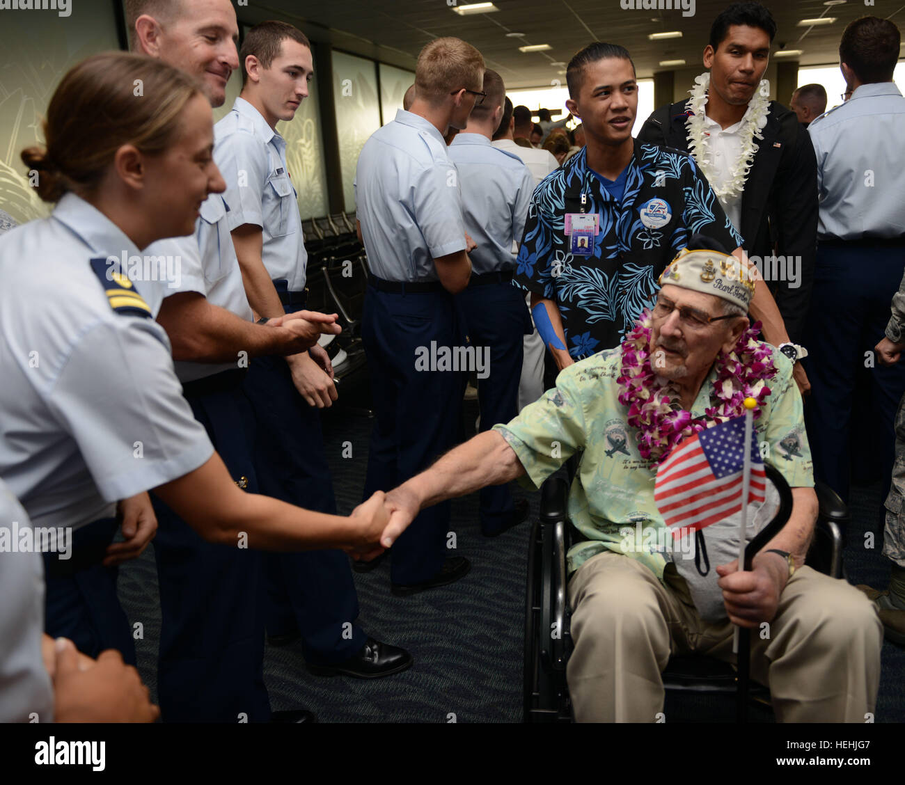 Eine Veteran des zweiten Weltkriegs Pearl Harbor USA wird von US-Küstenwache Offiziere mit floralen Leis begrüßt, nach der Ankunft am internationalen Flughafen Honolulu zur Teilnahme an Veranstaltungen zum Gedenken zu Ehren des 75-jährigen Bestehens des Pearl Harbor Angriffen 3. Dezember 2016 in Honolulu, Hawaii. Stockfoto