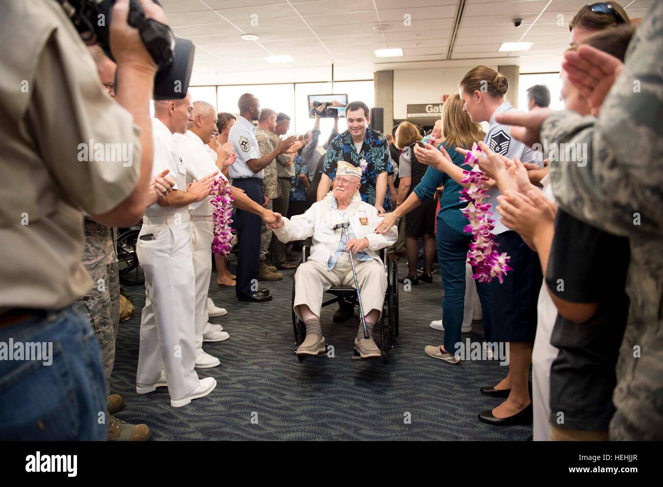 Eine Veteran des zweiten Weltkriegs Pearl Harbor USA wird von US-Soldaten mit floralen Leis begrüßt, nach der Ankunft am internationalen Flughafen Honolulu zur Teilnahme an Veranstaltungen zum Gedenken zu Ehren des 75-jährigen Bestehens des Pearl Harbor Angriffen 3. Dezember 2016 in Honolulu, Hawaii. Stockfoto