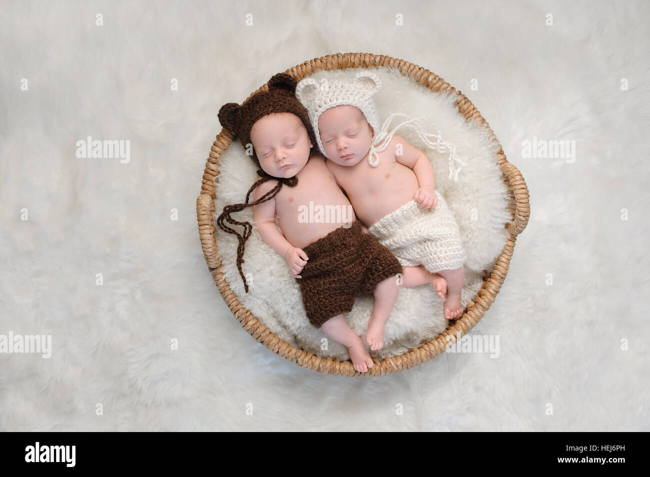 Zwei Monate alten Jungen und Mädchen brüderlichen zwei Babys. Sie schlafen zusammen in einem Korb koordinierte, gehäkelte, Bär Motorhauben und Shorts tragen. Stockfoto