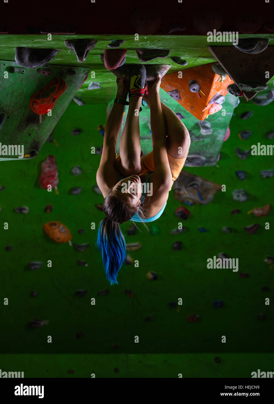 Junge Frau Bouldern an Decke der Kletterhalle Stockfoto