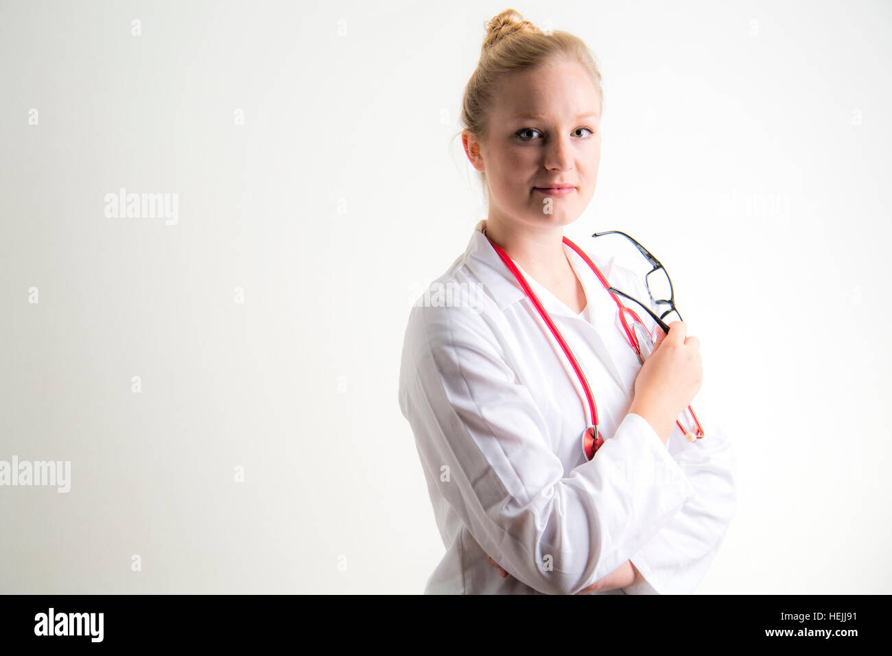 UK Health Care Professionals: A National Health Service (NHS) weibliche Ärztin trägt einen weißen Mantel und mit einer roten Stethescope um den Hals Stockfoto