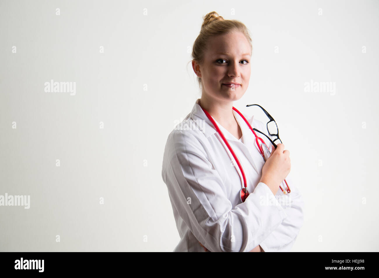 UK Health Care Professionals: A National Health Service (NHS) weibliche Ärztin trägt einen weißen Mantel und mit einer roten Stethescope um den Hals Stockfoto