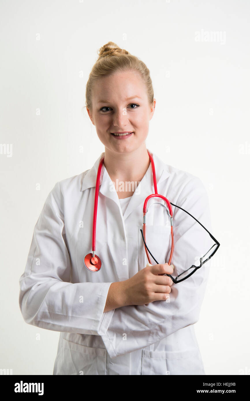 UK Health Care Professionals: eine glücklich lächelnde National Health Service (NHS) weibliche Ärztin trägt einen weißen Mantel und mit einer roten Stethescope um den Hals Stockfoto