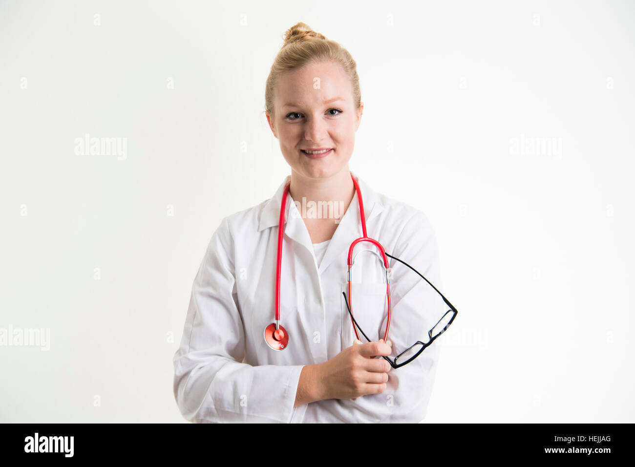 UK Health Care Professionals: eine glücklich lächelnde National Health Service (NHS) weibliche Ärztin trägt einen weißen Mantel und mit einer roten Stethescope um den Hals Stockfoto
