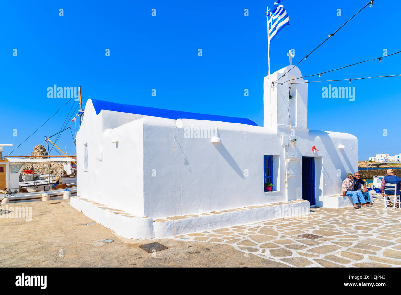 Insel PAROS, Griechenland - 20. Mai 2016: Fischer sitzt vor einer Kirche in Naoussa Hafen auf der Insel Paros, Griechenland. Stockfoto