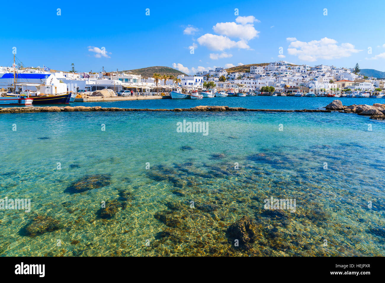 Kristallklares Meerwasser in Naoussa Bucht mit Hafen in Ferne, Insel Paros, Griechenland Stockfoto