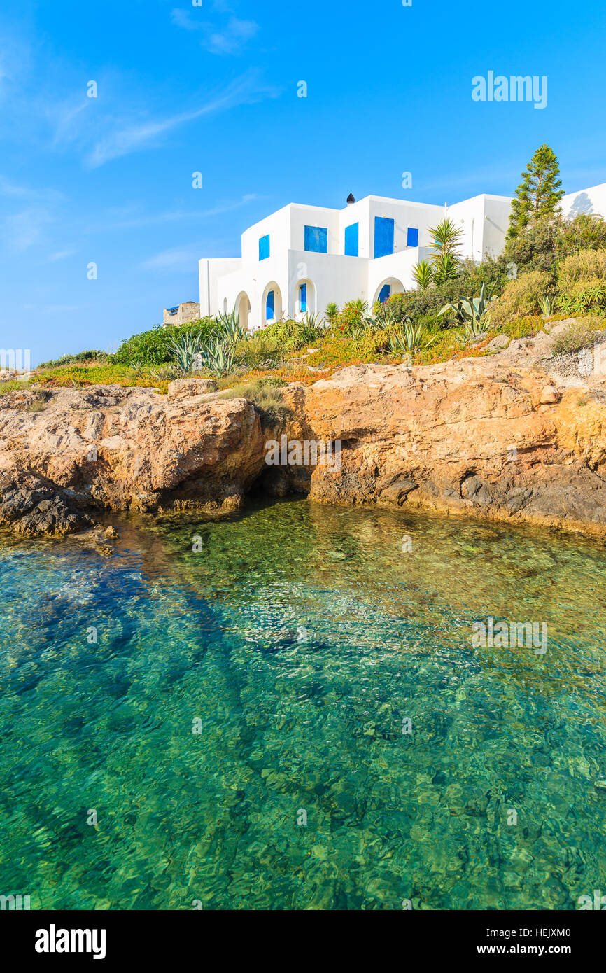 Weiße typisch griechisches Haus auf der Klippe mit Blick auf die wunderschöne Bucht mit kristallklarem Meerwasser, Naoussa Village, Insel Paros, Kykladen, Griechenland Stockfoto