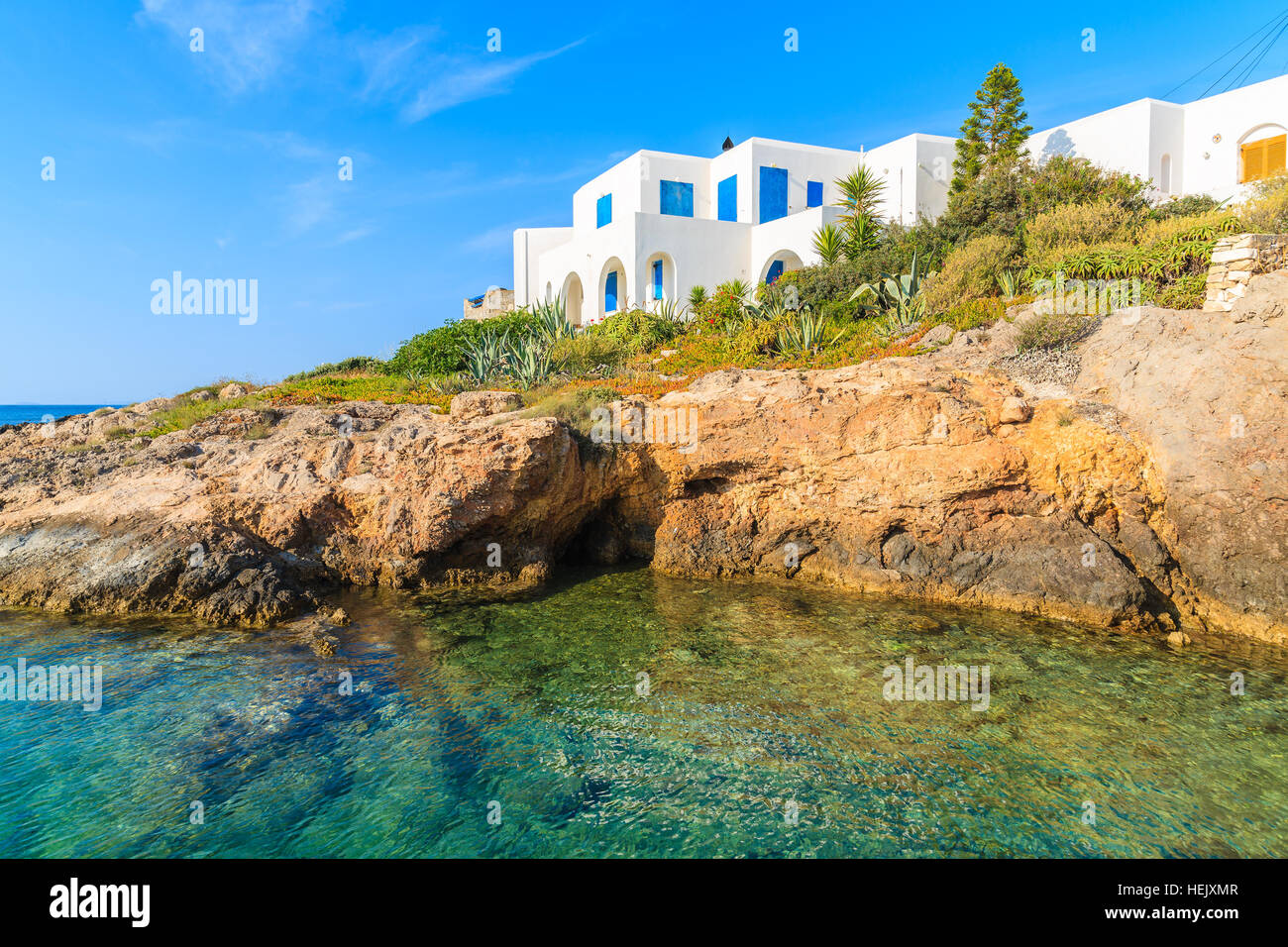 Weiße typisch griechisches Haus auf der Klippe mit Blick auf die wunderschöne Bucht mit kristallklarem Meerwasser, Naoussa Village, Insel Paros, Kykladen, Griechenland Stockfoto