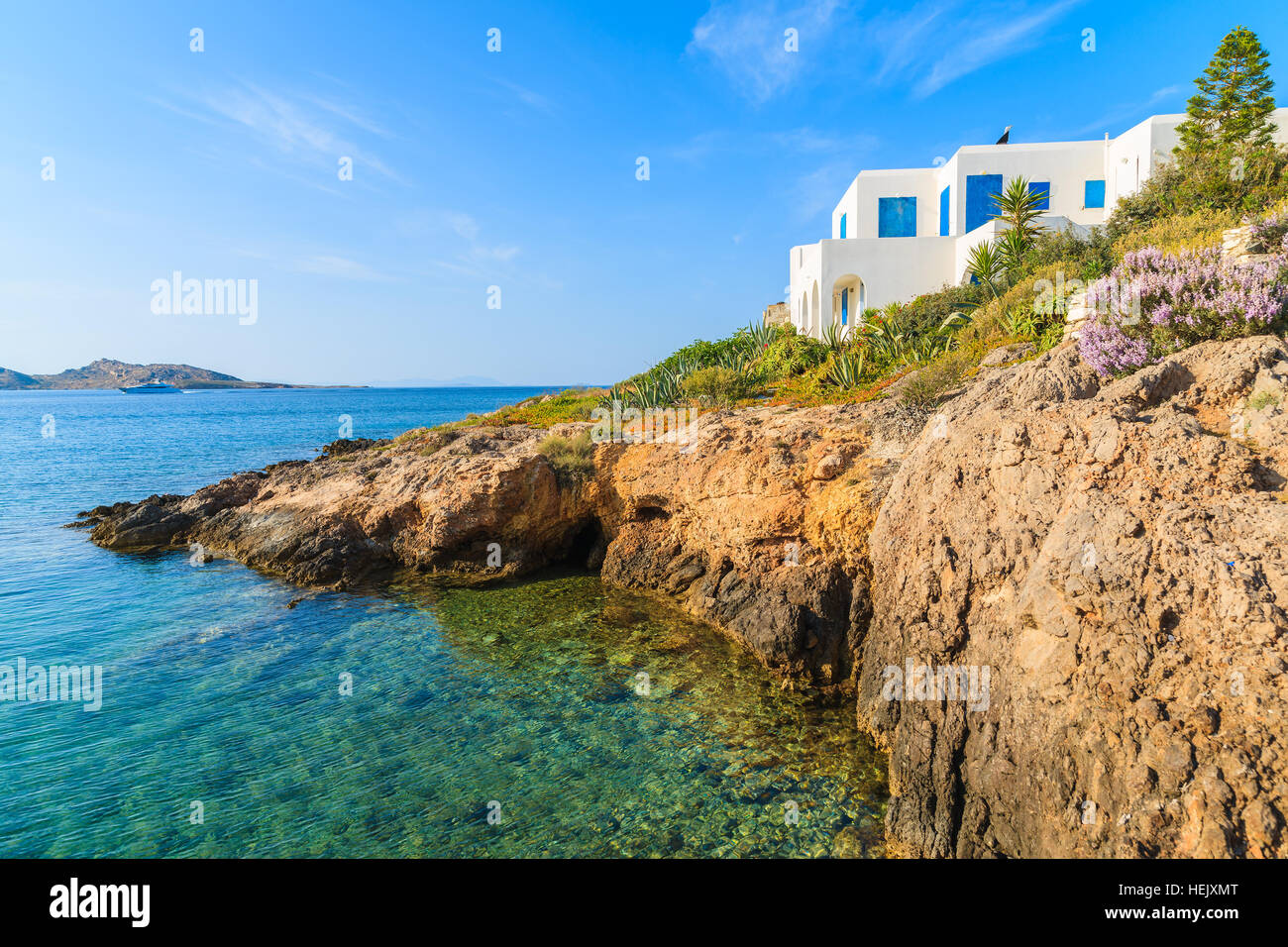 Weiße typisch griechisches Haus auf der Klippe mit Blick auf die wunderschöne Bucht mit kristallklarem Meerwasser, Naoussa Village, Insel Paros, Kykladen, Griechenland Stockfoto