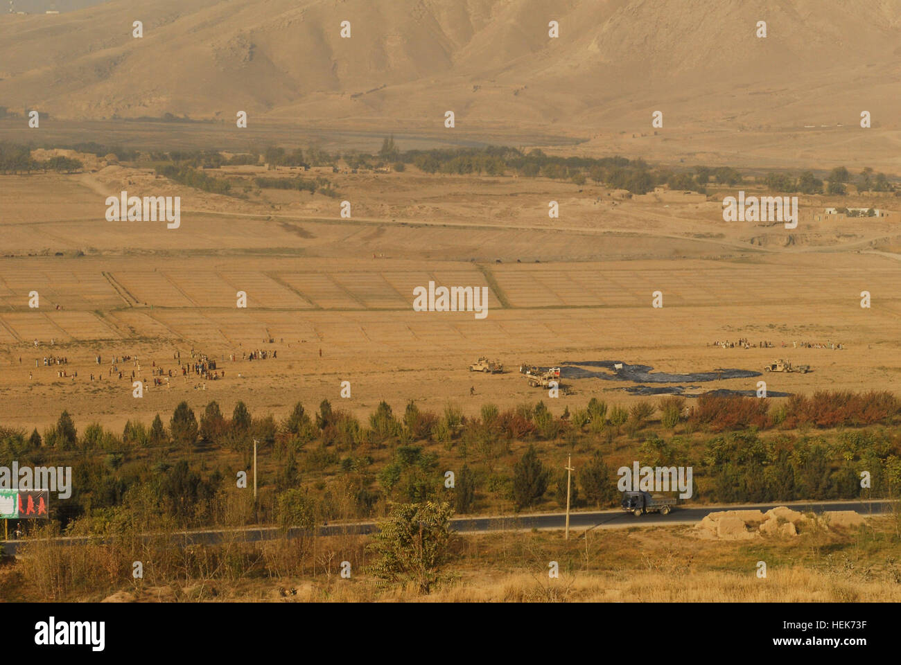 Mehr als hundert Dorfbewohner sammeln, Hoffnung, eine Fallschirm Überdachung, greifen da US Special Forces Behälter für Lebensmittel und Vorräte in einem Feld unterhalb Außenposten Nord, Baghlan Provinz Okt. 30 Luft abgeworfenen abrufen. (Foto von Sgt. Katryn McCalment) Straße in Baghlan Stockfoto