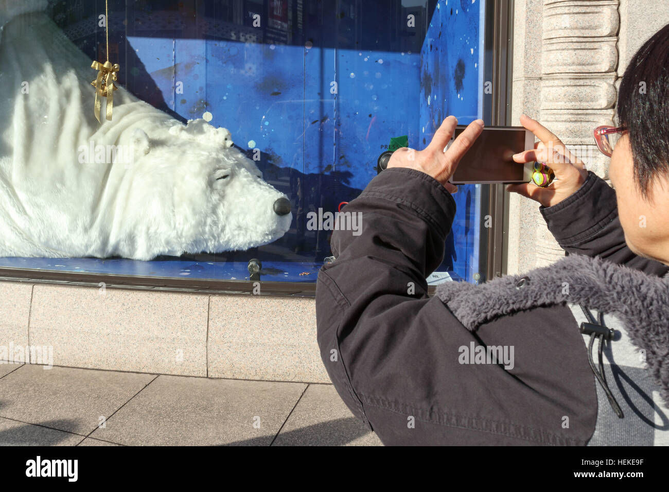 Eine Ginza Shopper fotografiert ein riesiger Eisbär auf dem Display an Wako Kaufhaus am 21. Dezember 2016, Tokio, Japan. Die Schaufensterauslage umfasst eine große Bärin mit zwei Babys schlafen. Fußgänger dürfen Aufwachen der größte Bär treibt eine Unterseite, die sagt, "Bitte nicht stören." © Rodrigo Reyes Marin/AFLO/Alamy Live News Stockfoto