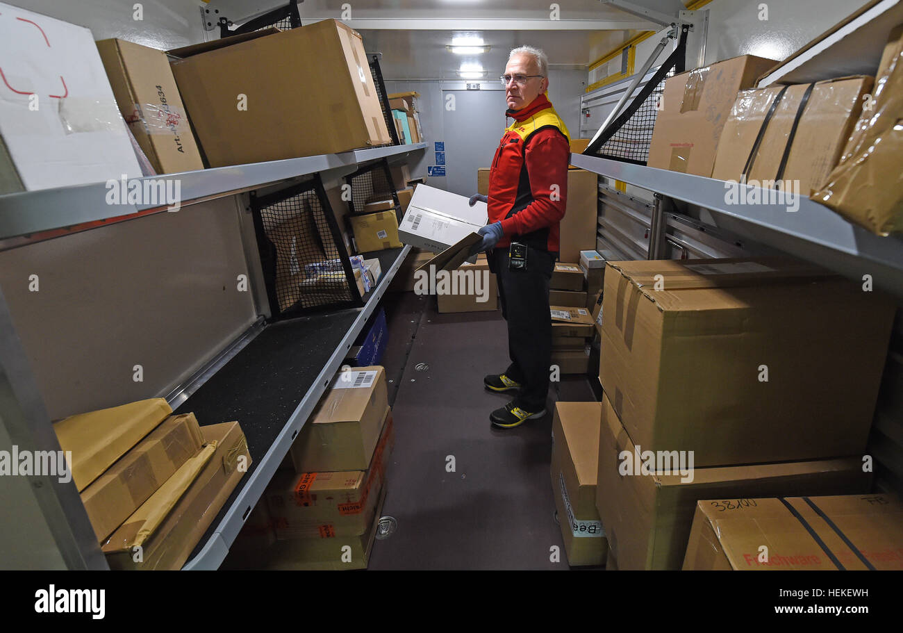 Die Paket-Zusteller Hans-Joachim Harnagel trägt eine Paket in seinem Post-Fahrzeug bei der DHL-Lieferung Basis Braunschweig, Deutschland, 21. Dezember 2016. Danach liefert Harnagel Päckchen und Pakete an die Empfänger während einer Reise durch die Innenstadt von Braunschweig. Foto: Holger Hollemann/dpa Stockfoto