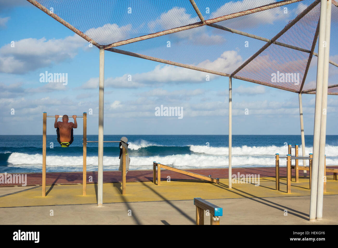 Mann tut Pull Ups mit Blick auf Stadtstrand in Las Palmas, Gran Canaria, Kanarische Inseln, Spanien. Stockfoto