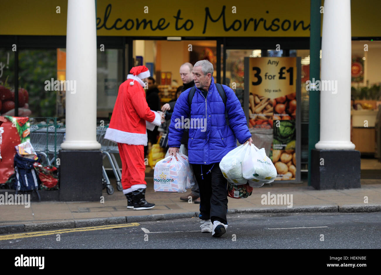Brighton UK 23. Dezember 2016 - beladen mit Taschen Shopper pass von einem Big Issue Verkäufer als Weihnachtsmann verkleidet, beim Verlassen eines Safeway-Supermarkts in Brighton mit heute voraussichtlich die verkehrsreichsten Weihnachts-Essen shopping-Tag der festlichen Zeit in Großbritannien Credit: Simon Dack/Alamy Live News Stockfoto