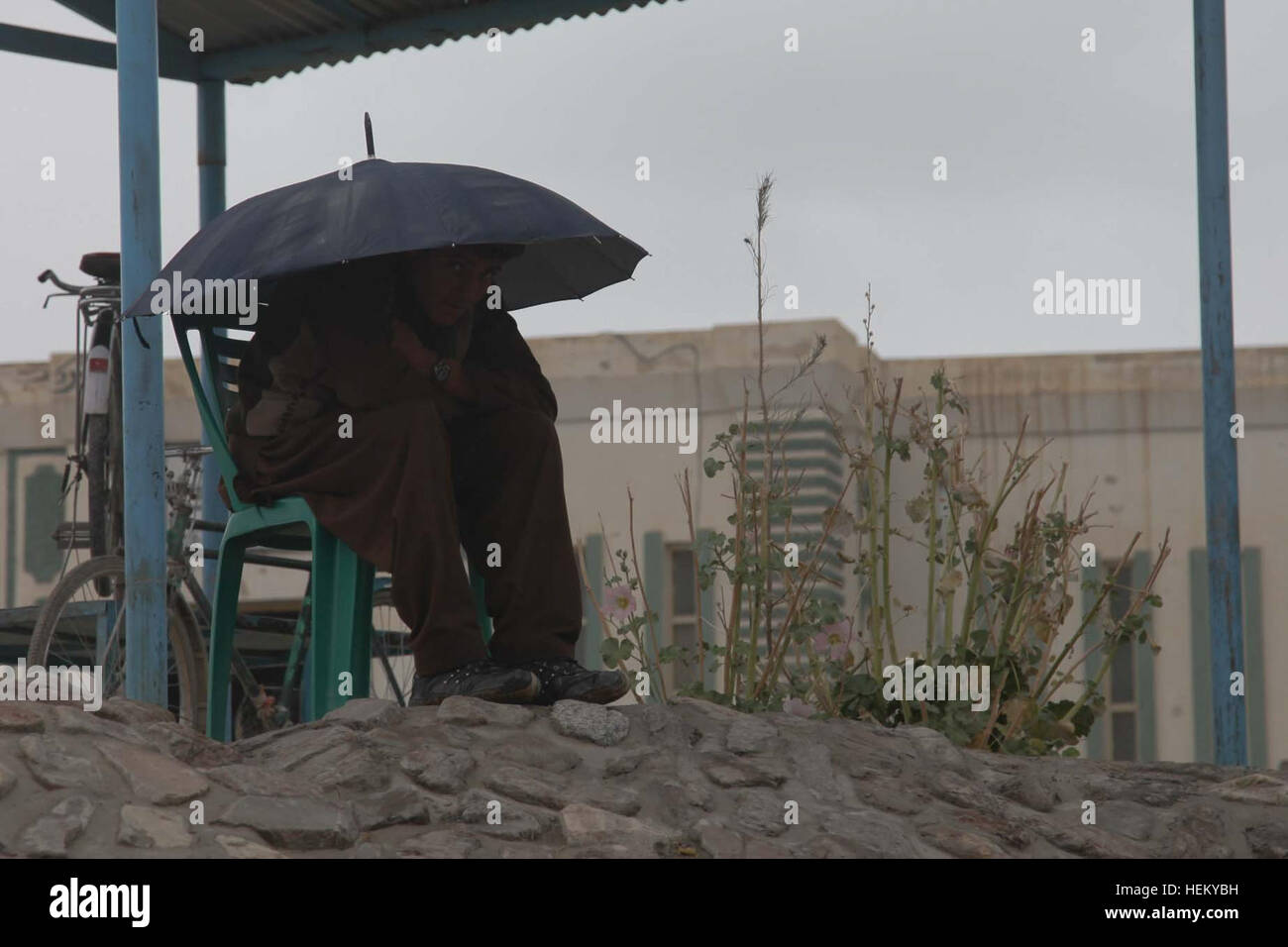 Ein afghanische Kind schmiegt sich unter einem Sonnenschirm aus dem Regen während der Aussparung am Jamaludin Wardak Coed High School, Sra Kala, Provinz Wardak, Afghanistan, 11. Oktober 2011 bleiben. Wasserscheide Projekt 111011-A-ZI978-008 Stockfoto