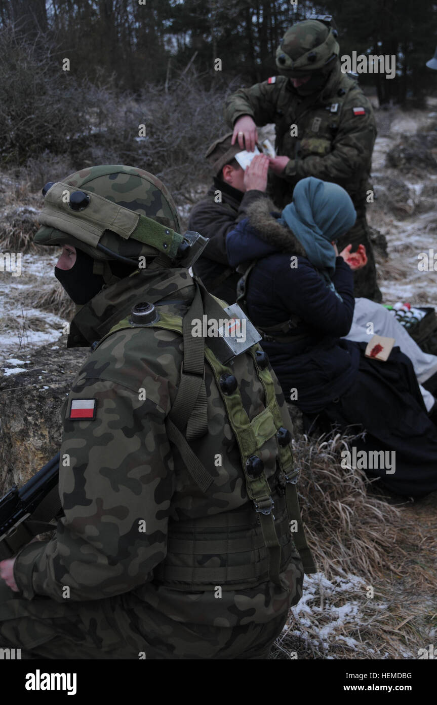 Ein polnischer Soldat zieht Sicherheit wie ein Kameraden medizinischen Hilfe zu simulierten Zivilunfall während einer militärischen Beratungsteam (MAT)-Übung auf der Joint Multinational Readiness Center in Hohenfels, Deutschland, 13. Januar 2013 verwaltet. Matten und Beratungsteams Polizei sollen replizieren die Einsatzumgebung Afghanistan während der Vorbereitung Teams für Aufstandsbekämpfung mit der Fähigkeit zu trainieren, beraten und ermöglichen die Afghanistan National Army und der Nationalpolizei Afghanistan.  (US Armee-Foto von Sgt. Kirk Evanoff/freigegeben) Beratungsteam von Polizei und Militär Adviso Stockfoto