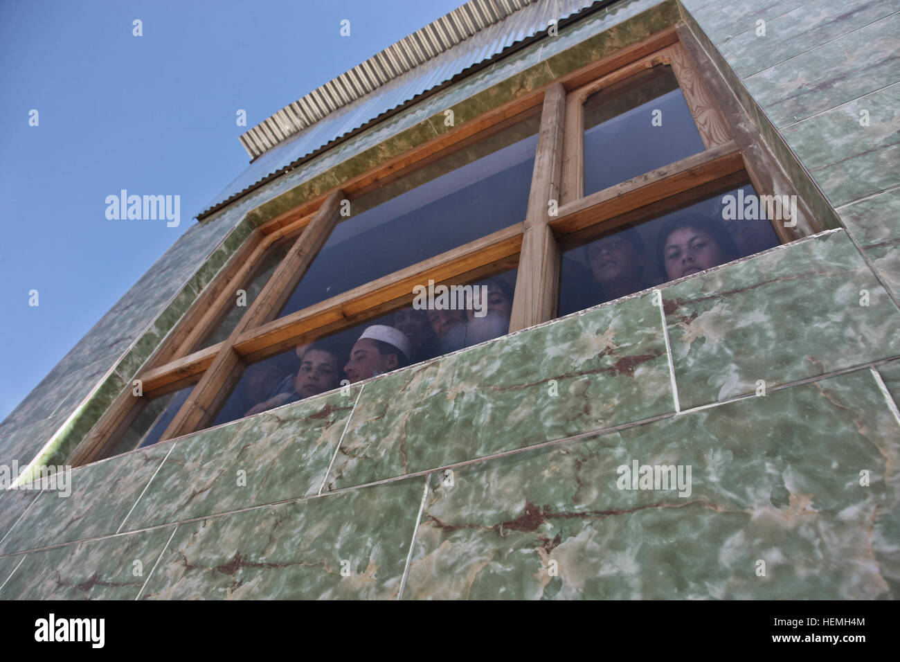 Afghanische Jungen schauen aus dem Fenster auf die All-Boys Paschtu Abad School in Ghazni Bezirk, Provinz Ghazni, Afghanistan, 20. April 2013. Khalilullah Hotak, ein Mitglied der Provinz Nejat sozialen Rat von Ghazni verteilte Rucksäcke und Schreibtische für die Schule, die mehr als 600 jungen unterrichtet. Die Nejat Sozialrat Ziel ist es, Unterdrückung, Korruption und Ungerechtigkeit in Abstimmung mit der afghanischen Regierung zu beseitigen.  (US Armee-Foto von Spc. Jessica Reyna DeBooy/freigegeben) Pashtu Abad Schule 130420-A-SL739-268 Stockfoto