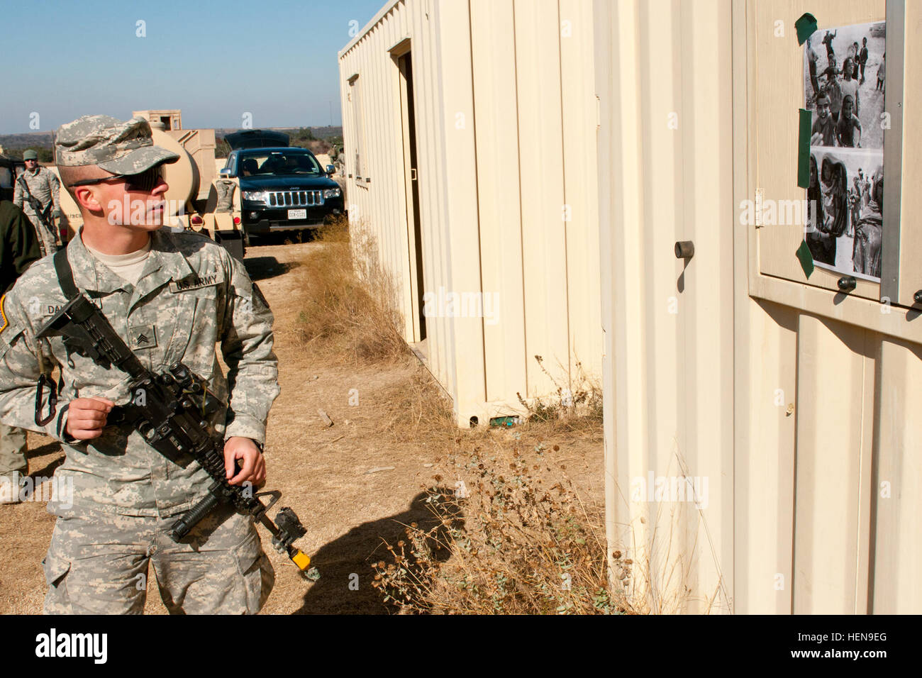 US Armee Sgt. Zachary Daugherty, Teamleiter für die 1. Staffel, 3. Kavallerie-Regiment, merkt sich die Gesichter auf Fotos, die eine Conex in ein Hindernis-Parcours eingerichtet, um die Verbesserung der Handlungskompetenz 10. Dezember 2013 testen mit Klebeband befestigt wurden. Soldaten wurden durch ein Labyrinth von Conexes mit verschiedenen Fotos, die mit Klebeband an sie innen und außen, mit anderen Hindernissen wie Stolperdrähte und mögliche improvisierte Sprengsätze in der Gegend verstreut, und dann gebeten, passen die Fotos und die Gefahr Elemente auf Karten zu markieren, sobald sie zum Ausgangspunkt zurück geschickt. Die Tests wurden von Meister Widerstandsfähigkeit Traine entwickelt. Stockfoto