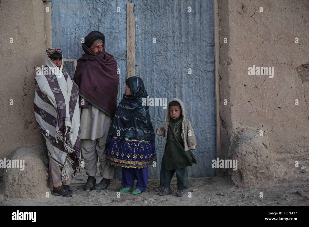 Afghanische Dorfbewohner außerhalb der eigenen Wohnung stehen und zusehen, wie afghanischen nationalen Sicherheitskräfte während einer Clearing-Operation in Shah Freude Bezirk, vorbei bewegen Zabul Provinz, Afghanistan, 28. Dezember 2013. Während der Operation zwei Aufständische Verdächtige wurden festgenommen und mehrere improvisierte Sprengkörper Materialien wurden zerstört. (Foto: U.S. Army Pfc David Devich / veröffentlicht) Afghanischen nationalen Sicherheitskräfte Operationen in Shah Freude Bezirk 131228-A-XP365-349 Stockfoto