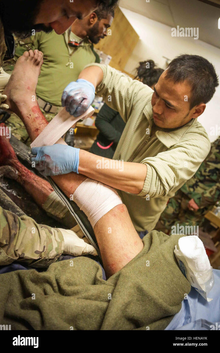 Eine afghanische Nationalarmee Medic, unterstützt von US-Militärangehörige, gilt Gaze eine Schiene halten Sie für ein Afghan National Army Soldat verwundet in Shah Freude Bezirk Zabul Provinz, Afghanistan, 24. Januar 2014. Der Soldat erlitt Schussverletzungen auf beide Beine bei einem Feuergefecht mit Aufständischen im Distrikt Shah Freude. (Foto: U.S. Army Pfc David Devich / veröffentlicht) Soldaten der afghanischen Nationalarmee und US-Angehörige bieten medizinischen Behandlung für ein Afghan National Army Soldat verwundet in Shah Freude District, Provinz Zabul 140124-A-XP635-044 Stockfoto