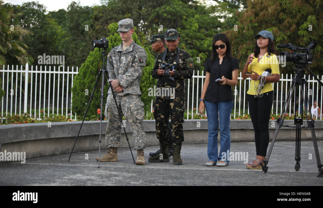 US Army Spc Matthew Hulett von 55. Signal Company (Combat Camera), links, und der philippinischen Armee CPL. Jonas Ballosteros aus dem 20. Infanterie-Bataillon, 8. US-Infanteriedivision, zweiter von links, entlang werden lokale Nachrichten-Agenturen dokumentieren die Pangatian Krieg Kranz Verlegung Gedenkfeier am Cabanatuan City, Philippinen Balikatan 2014, 10. Mai 2014.  Während des zweiten Weltkriegs half den Cabanatuan City US Rangers und Pfadfinder durch die Bereitstellung von Nahrung, Wasser und Transport von ambulanten Patienten.  Dieses Jahr markiert die 30. Iteration der Übung, die eine jährliche Republik der Philippinen Stockfoto